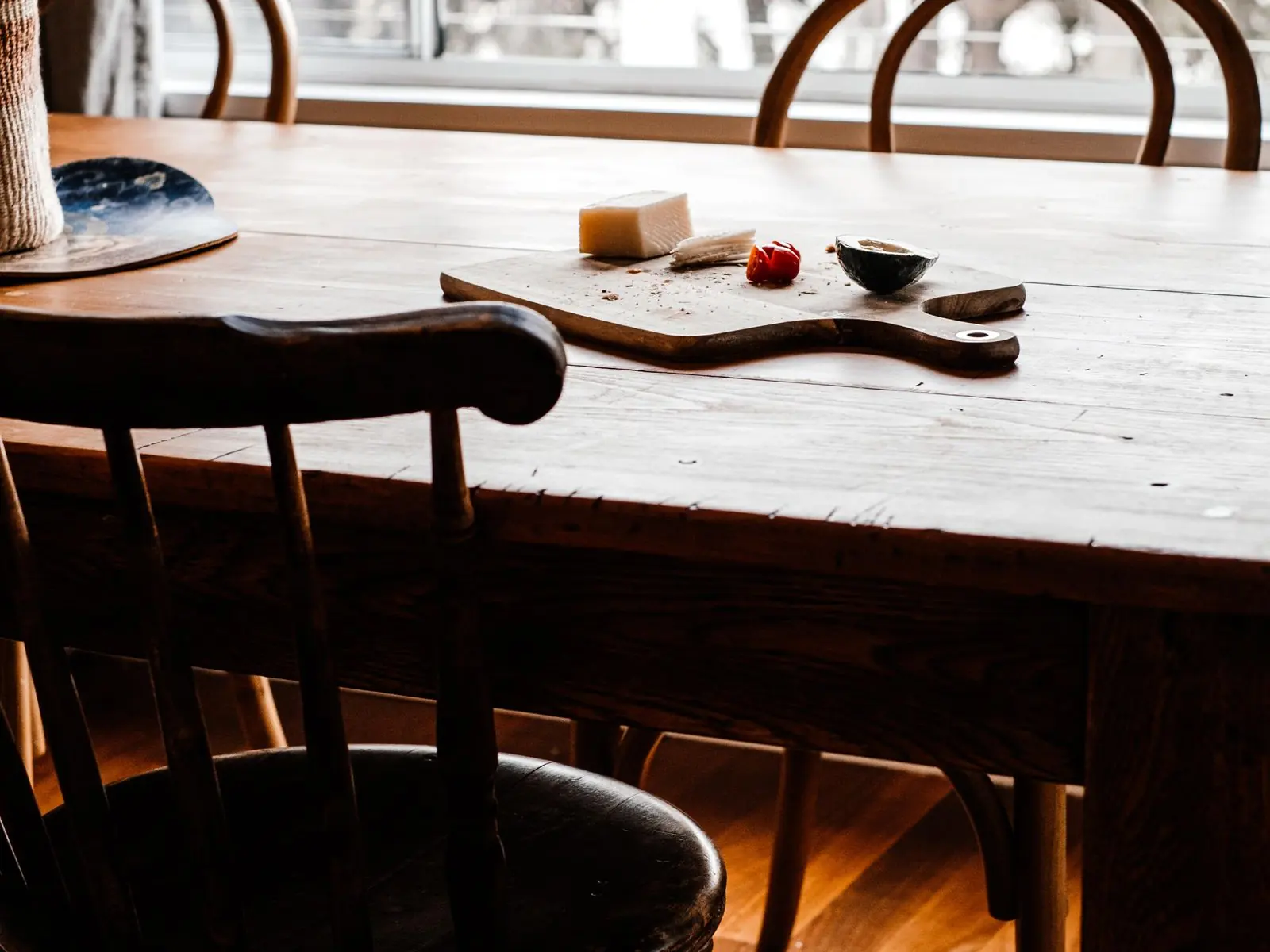 Mesa de comedor de madera con las sillas vacías, junto a la ventana de una casa