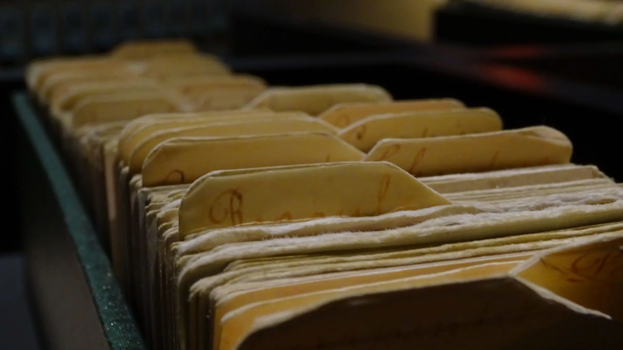 Fichas y expedientes ordenados en el cajón de un archivo, a media luz